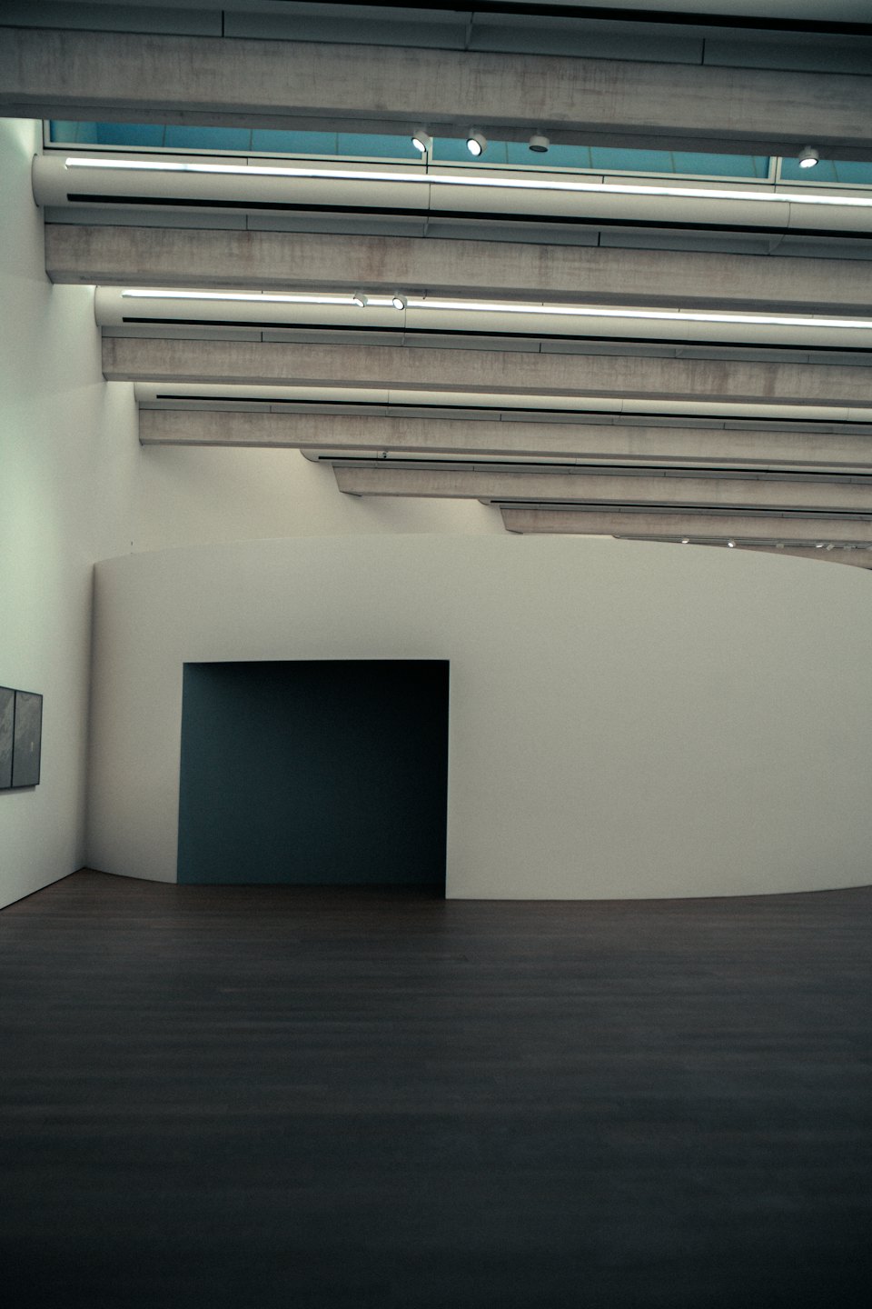 Pusta galeria sztuki nowoczesnej z szarymi ścianami i drewnianą podłogą.